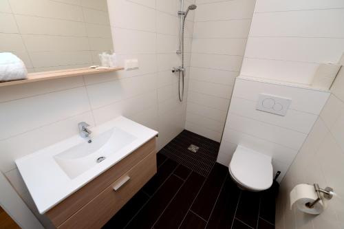 a white bathroom with a sink and a toilet at Premium Apartments am Weißensee in Weissensee