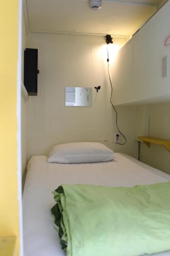 a bed in a small room with a light on the wall at The hostel kobe in Kobe