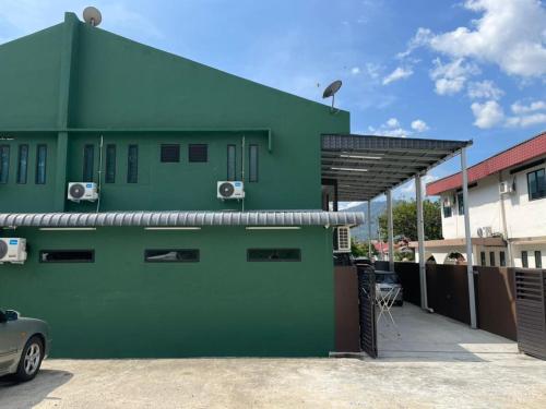 a green house with a car parked in front of it at Ipoh TZY's Homestay in Ipoh