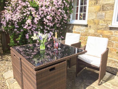 a table with a vase of flowers and two chairs at Smugglers View Nr Whitby in Ravenscar