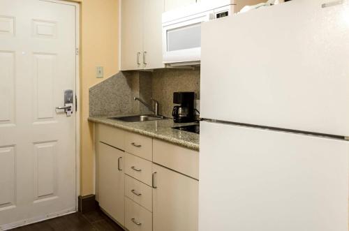 a kitchen with a white refrigerator and a sink at Rodeway Inn Vicksburg in Vicksburg