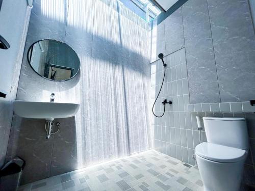 a bathroom with a toilet and a sink and a mirror at X Hostel Jogja in Timuran