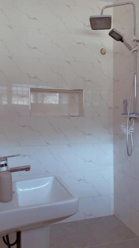 a white bathroom with a sink and a shower at Q2Shortlet Apartment in Isheri-Olofin