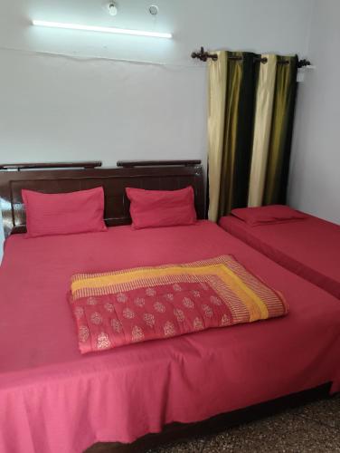 a bedroom with two beds with pink sheets at Thakur Shri Dwarkadhish Seva Sadan in Mathura