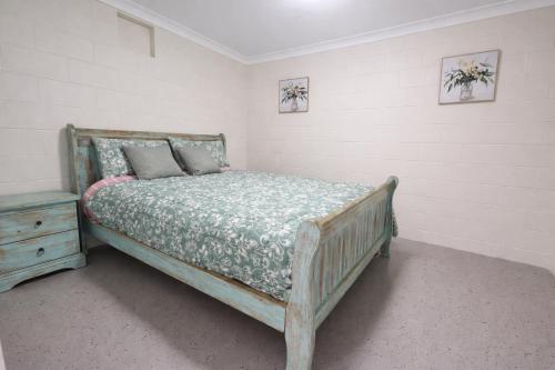 a bedroom with a wooden bed and a night stand at Kookaburra Guesthouse in Coffs Harbour