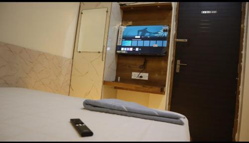 a room with a bed with a television and a remote control at Tokyo Inn in Howrah