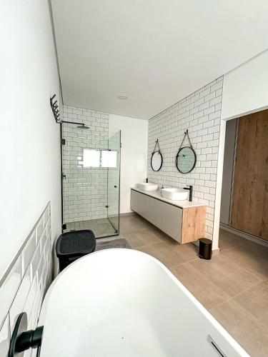 a white bathroom with a tub and a sink at Grace Eleven in Stompneusbaai