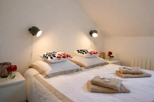 una camera da letto con un grande letto bianco con asciugamani sopra di Les Terrasses a Barneville-Carteret