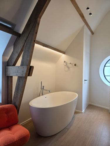 a bathroom with a large white tub in a attic at Castle B&B Castanea in Merelbeke