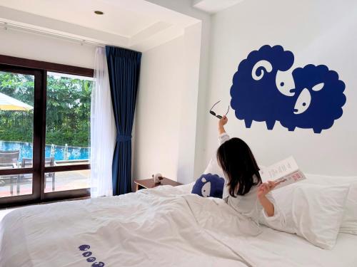 a young girl laying on a bed reading a book at Kokotel Khao Lak Montana in Khao Lak