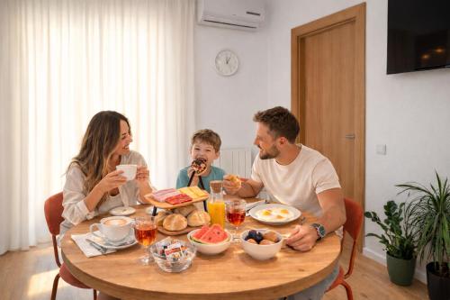Eine Familie sitzt an einem Tisch und isst. in der Unterkunft Villa Kuzmanić in Trogir