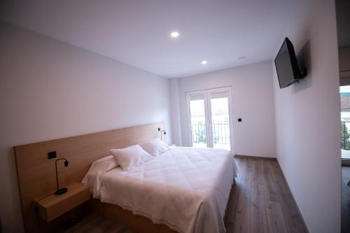 a white bedroom with a bed and a television at Casa Avó Libânia in Murça