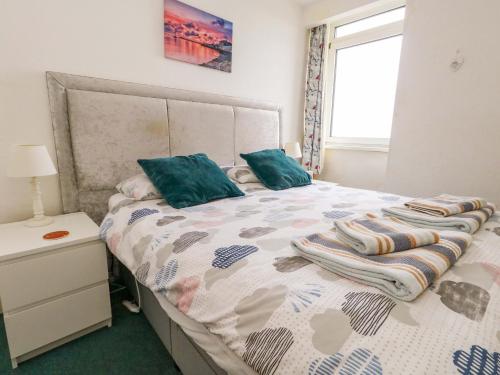 a bedroom with a bed with green pillows and a window at Bay View in Swanage