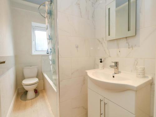a white bathroom with a sink and a toilet at Bay View in Swanage