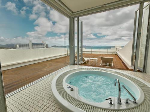 a bath tub in the middle of a room with a balcony at Hotel Greges in Munakata