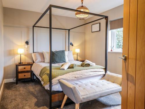 a bedroom with a canopy bed and a chair at Hafod Y Bryn in Harlech