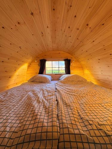 a large bed in a wooden room with a window at Campingfass im Naturresort Weserinsel in Langwedel
