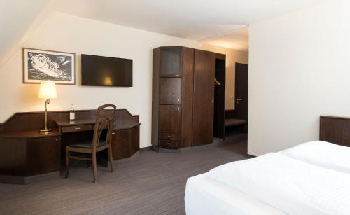 a hotel room with a desk and a bed and a bedroom at elaya hotel noerdlingen, Trademark by Wyndham in Nördlingen