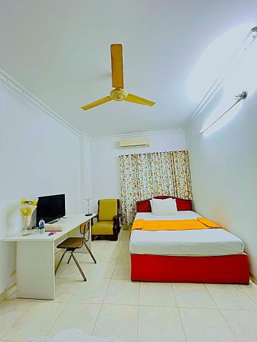 a bedroom with a bed and a desk and a ceiling fan at Maya Eco Guest House in Dhaka