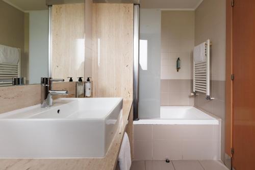 a bathroom with a white sink and a tub at Hotel Palau de Girona in Sant Julià De Ramis