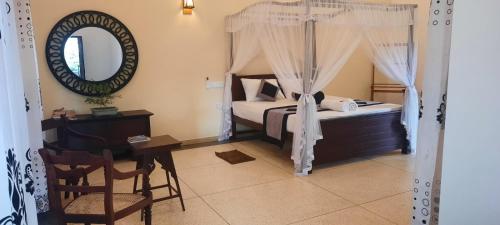 a bedroom with a bed and a desk and a mirror at Coco Villa in Talpe