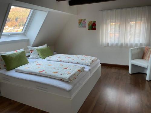 a white bedroom with a bed and a chair at Haus am Kastanienwald in Bad Bergzabern