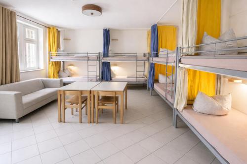 a room with bunk beds and a couch and a table at Königstein Hostel in Königstein an der Elbe