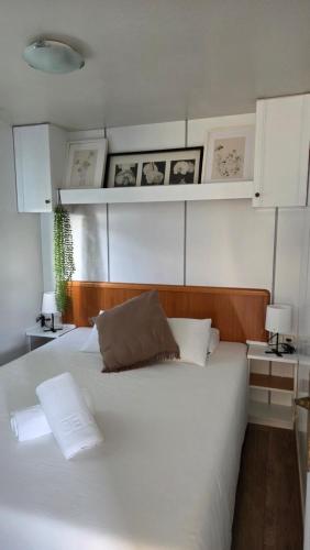 a bedroom with a large white bed with white cabinets at Area Parking Caravane in Seville