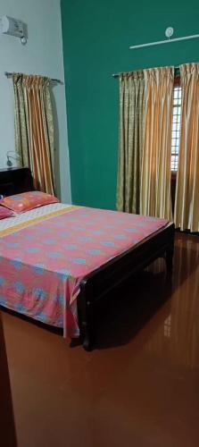 a bedroom with a bed with a red comforter at Villa in Chengannur in Māvelikara