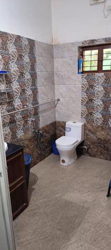a bathroom with a toilet and a stone wall at Villa in Chengannur in Māvelikara