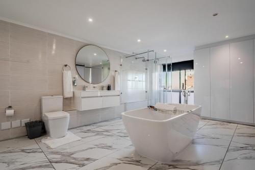 a bathroom with a tub and a toilet and a mirror at The Lighthouse in Cape Town