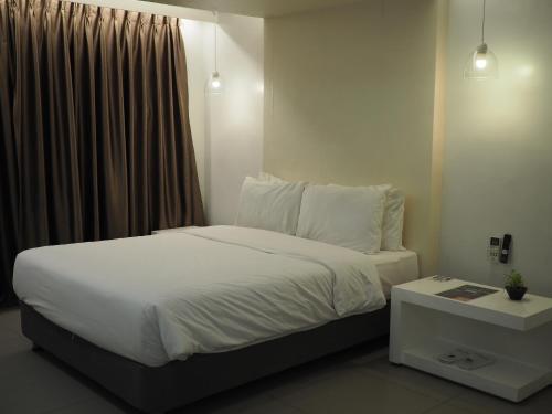 a bedroom with a bed with white sheets and a window at LeBlanc Hotel in Antipolo