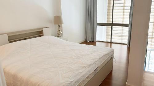 a white bed in a white bedroom with a window at 1 BR Loft Condo in Cha-Am in Cha Am