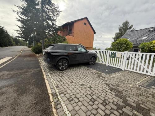 a black car parked next to a white fence at Apartament Premium Pola in Bolesławiec