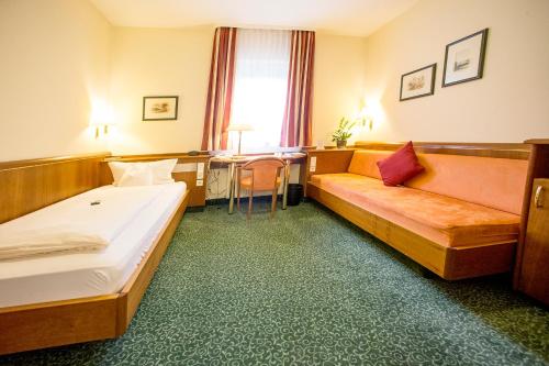 a hotel room with two beds and a table at Hotel Weisses Lamm in Veitshöchheim