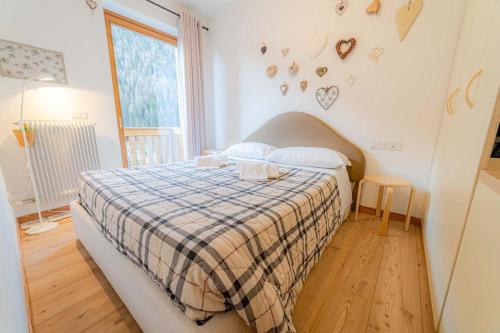a bedroom with a bed with a plaid blanket and a window at Appartamento Lucia in Penia