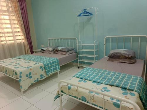 two beds in a room with blue walls at AZALEA Homestay Segamat in Segamat