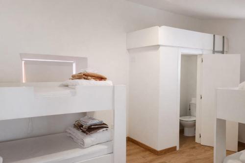 a white room with a bunk bed and a toilet at Pórtico del Azahín in Cazalla de la Sierra