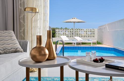 a living room with a table and a pool at Mythos Palace Resort & Spa in Georgioupolis