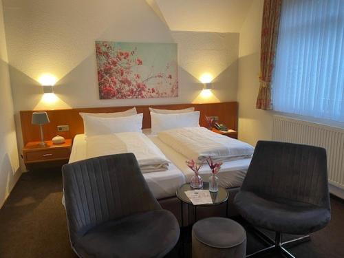 a hotel room with a bed and two chairs at Hotel Gasthaus Appel Krug in Delbrück