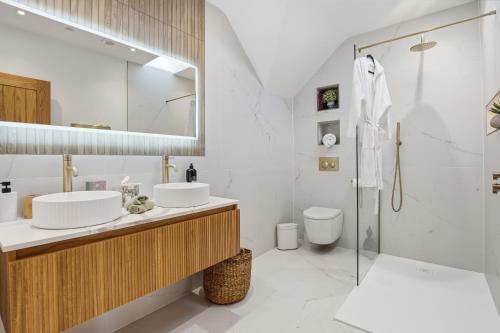 a white bathroom with two sinks and a shower at The Luxe Pool House, Westoning in Westoning