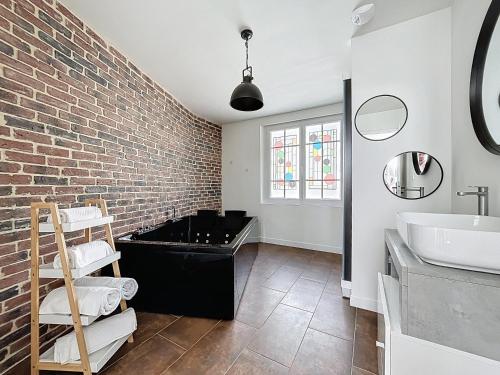 a bathroom with a sink and a brick wall at Appart Hôtel de la baie in Saint-Jean-le-Thomas