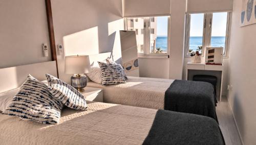 two beds in a room with a view of the ocean at Mackenzie Beachfront Panorama in Larnaca