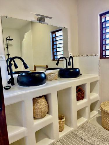 a bathroom with two sinks and a mirror at Le petit Relais 1 in Andilana