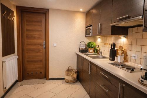 a kitchen with wooden cabinets and a door and a sink at Apartamenty Starka - aneks kuchenny, trasy spacerowe, szlaki turystyczne, pobyt z psem in Wisła