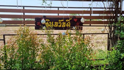 a sign on a fence with some plants and lights at Sinsawat Resort in Uttaradit