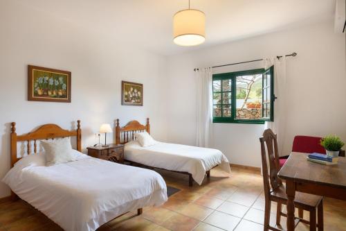 a bedroom with two beds and a desk and a table at Casa Crisana in Haría