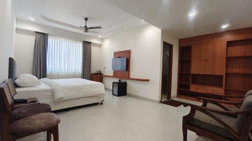 a bedroom with a bed and a tv and a chair at Darling Grand SME in Vellore