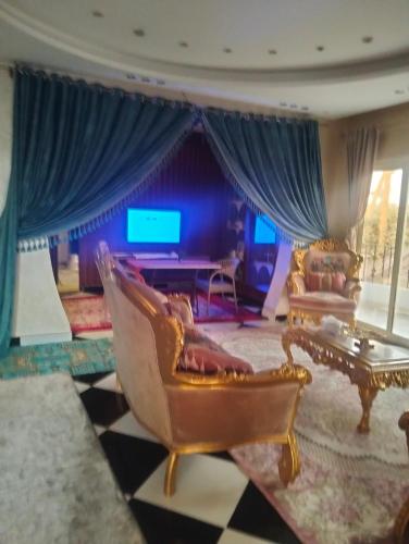 a living room with a couch and chairs and a tv at Ancient Bakyard Guesthouse in Abū Şīr