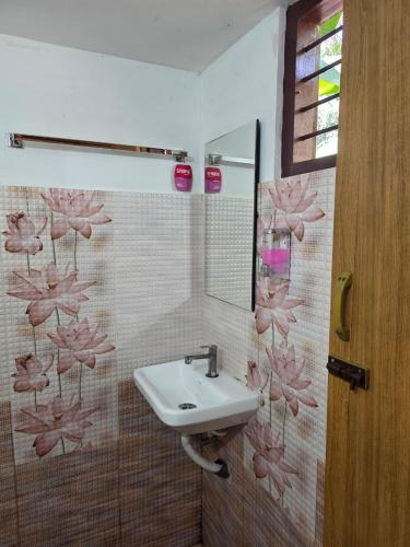 a bathroom with a sink and pink flowers on the wall at Ostello in Varkala